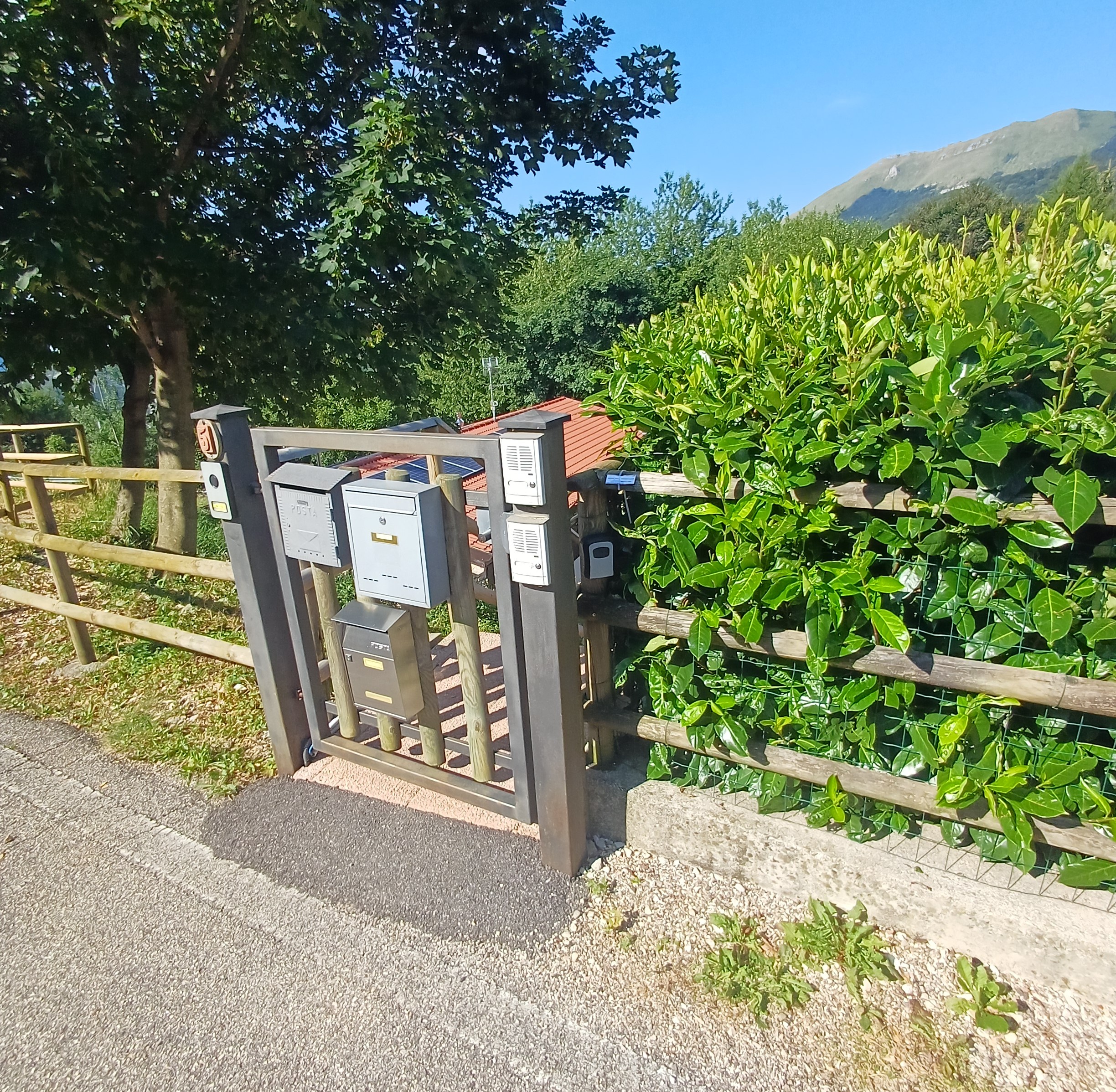 Cancelletto d’ingresso con lockbox nera accanto alle cassette postali